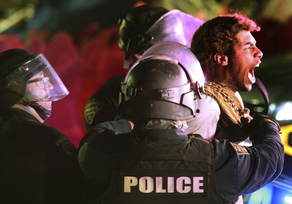 Tucson Police take a protester into custody on Park Avenue as law enforcement personnel from several area agencies clear an encampment of pro-Palestinian protesters from the University of Arizona campus, early Wednesday, May 1, 2024, in Tucson, Ariz.   (Kelly Presnell/Arizona Daily Star via AP)
